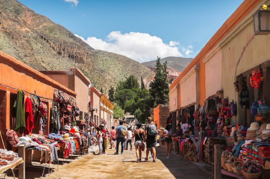 Explore a colorful outdoor market with traditional goods amidst scenic mountains.